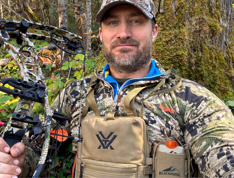 Man holding a bow and arrow in a forest setting